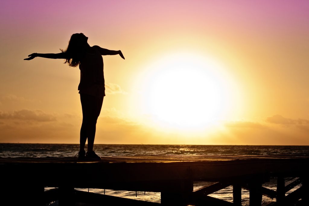 Woman with outstretched arms and sunset